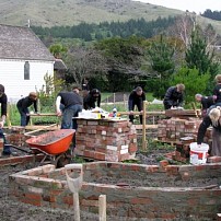 The Genesis Muck In team and locals building raised beds with bricks from the demolished Valley Inn.