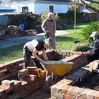 Volunteer gardeners building the first raise vegetable beds in Packe St Park with post quake chimney.