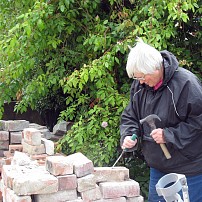 Volunteer gardener cleaning more bricks to make another bed.